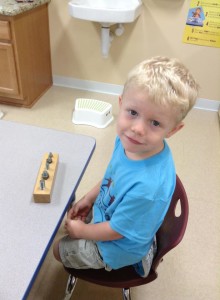 A young boy sitting in a chair using a toy Lutz Montessori School and Montessori at Trinity Oaks